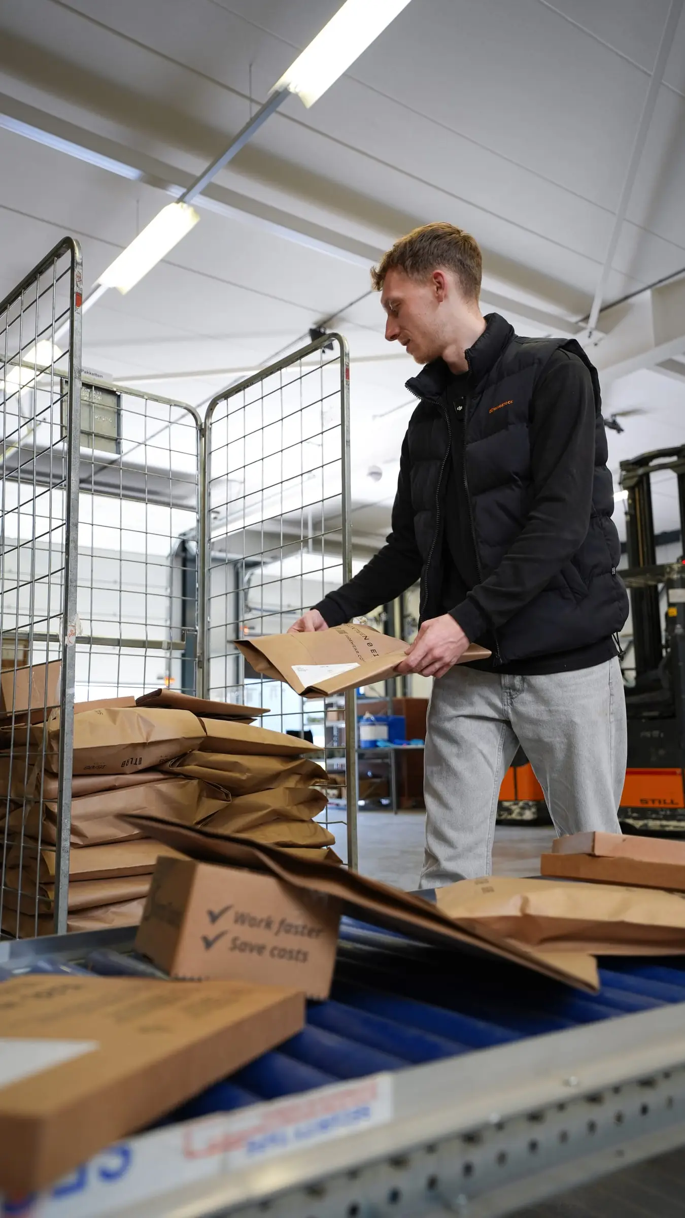 Een medewerker van Innostock pakt dozen uit op een lopende band in het magazijn.