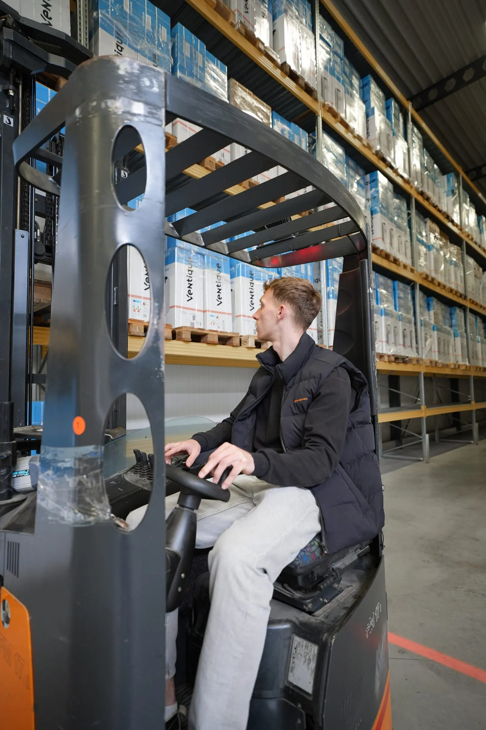 Een medewerker bestuurt een reachtruck, gezien van dichtbij.