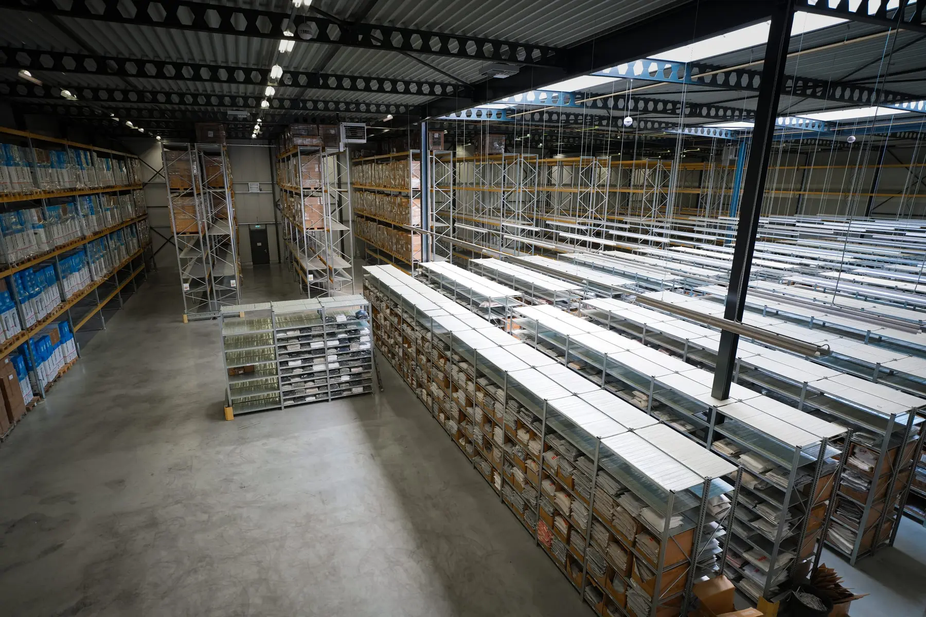 Overzicht van een magazijnhal met rollende stellingen en pallets.