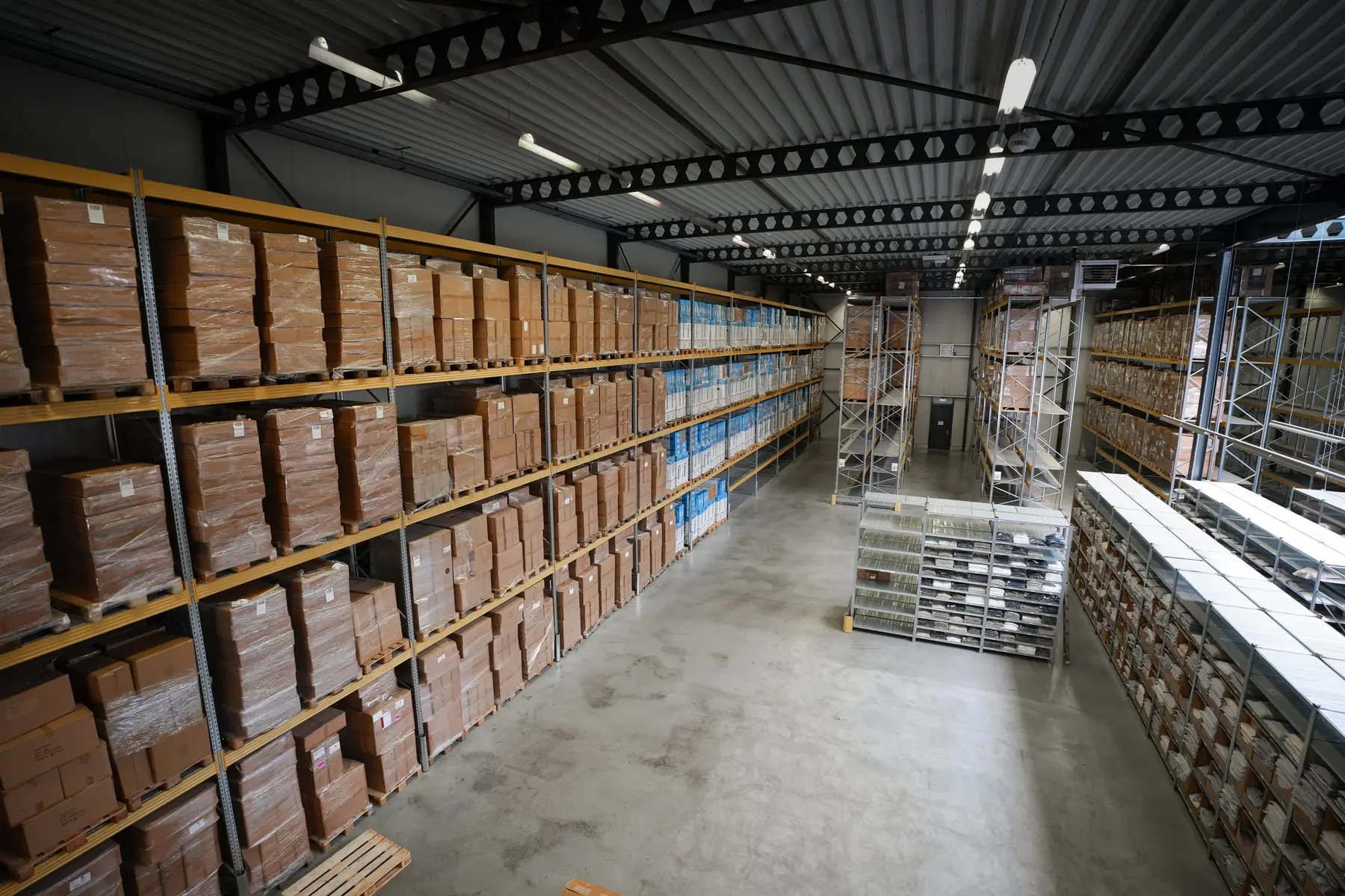 Een lange gang met stellingen vol dozen in het magazijn.