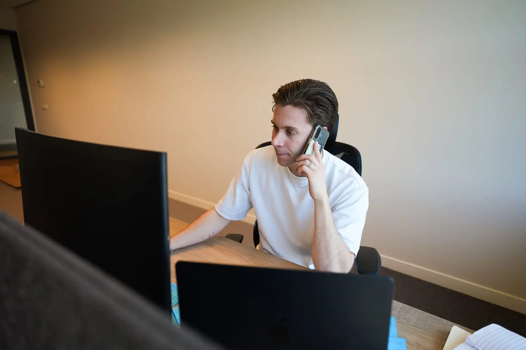 Een medewerker belt aan zijn bureau op kantoor.
