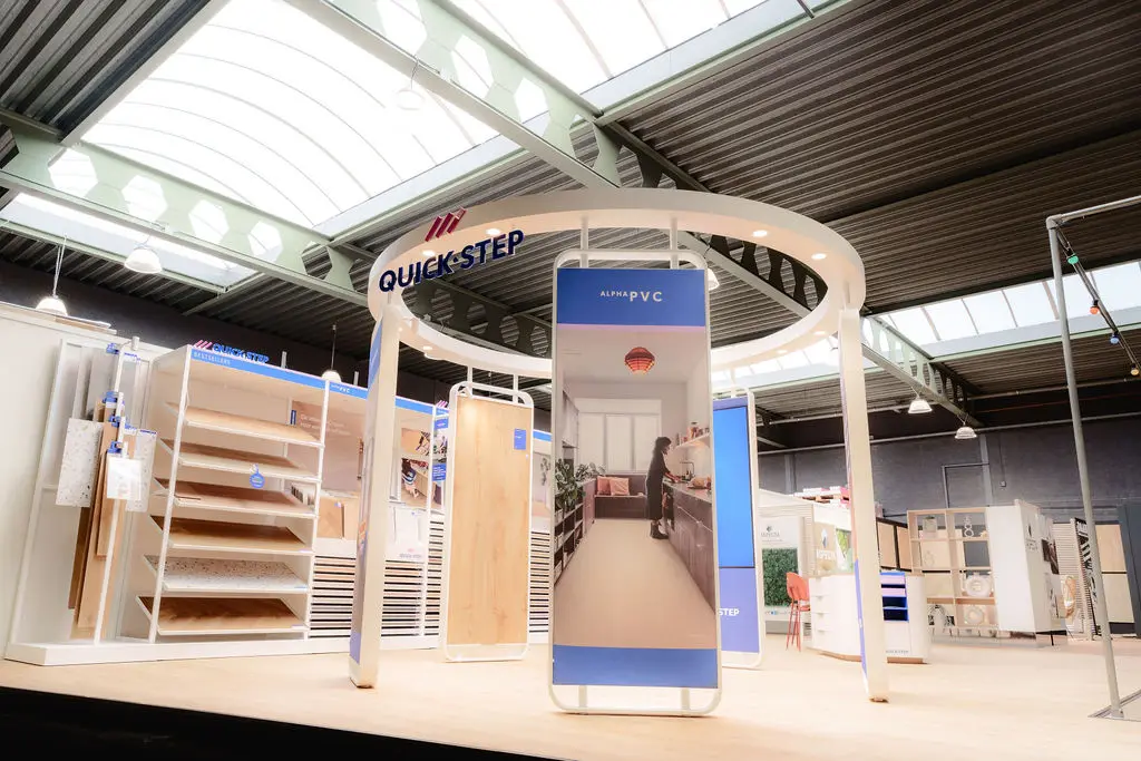 Een ronde presentatiestand in de showroom met vloerpanelen en een beeldscherm.