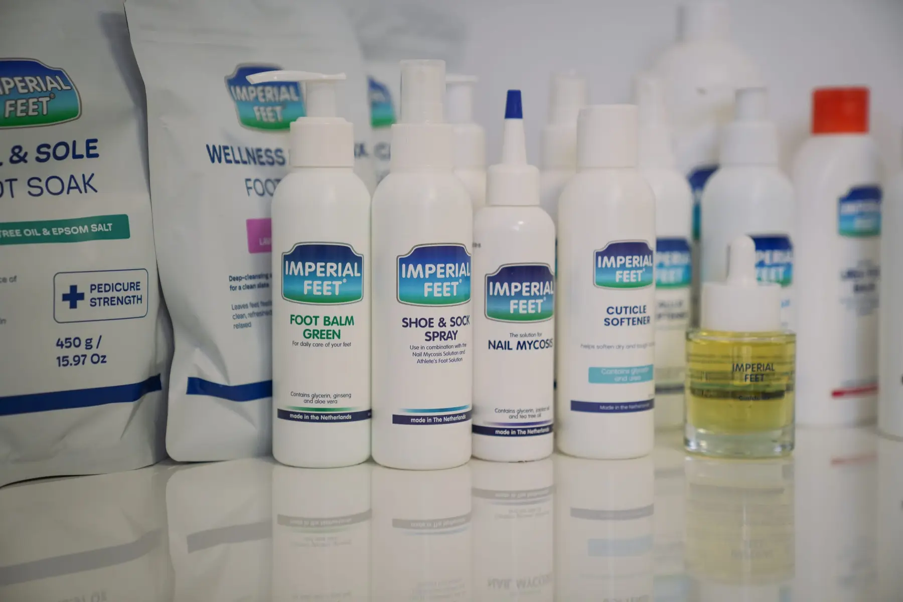 Een rij producten van Imperial Feet op een wit werkblad: zakken voetbad en flessen.