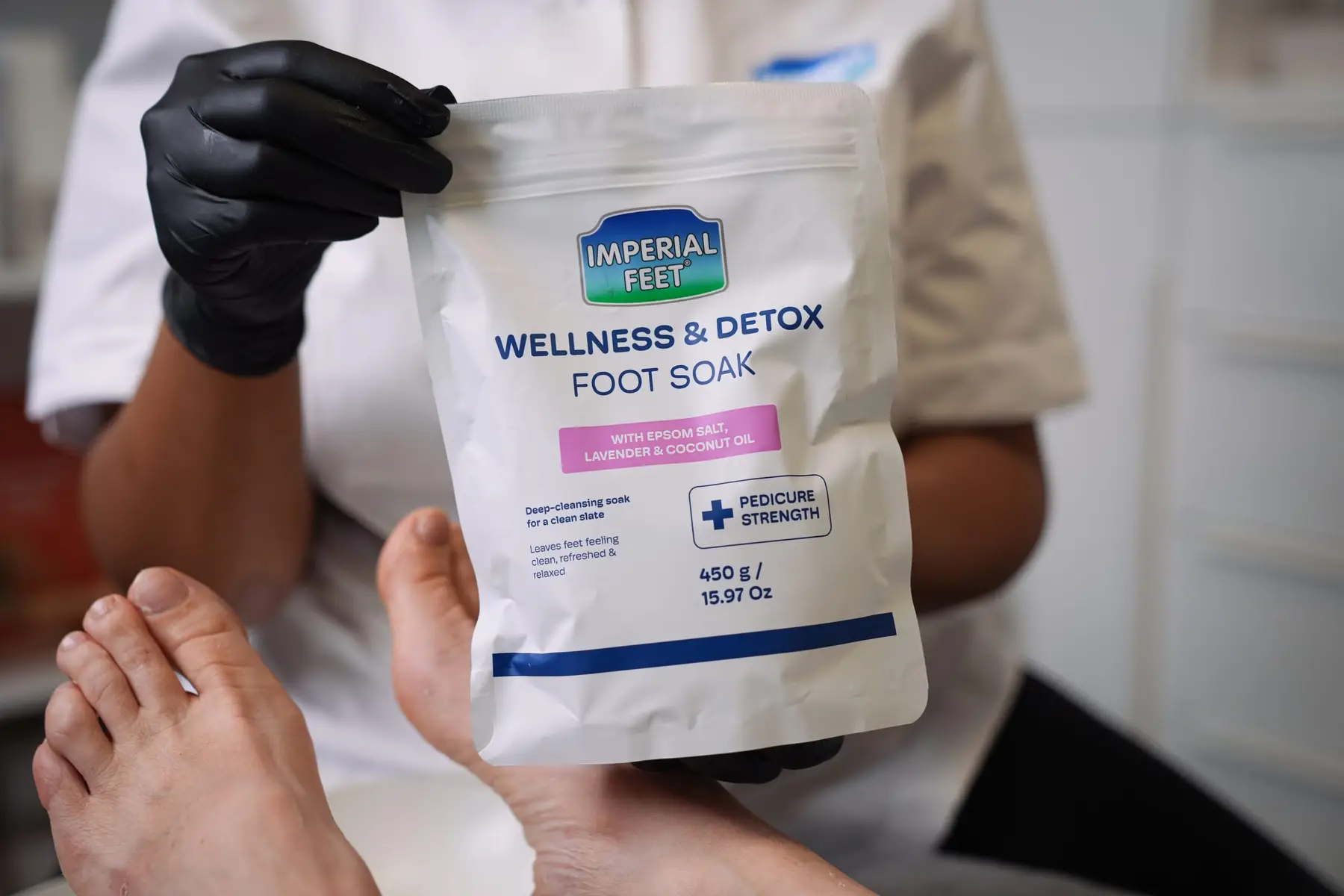 Een zak Wellness and Detox voetbad wordt vastgehouden naast een voet.