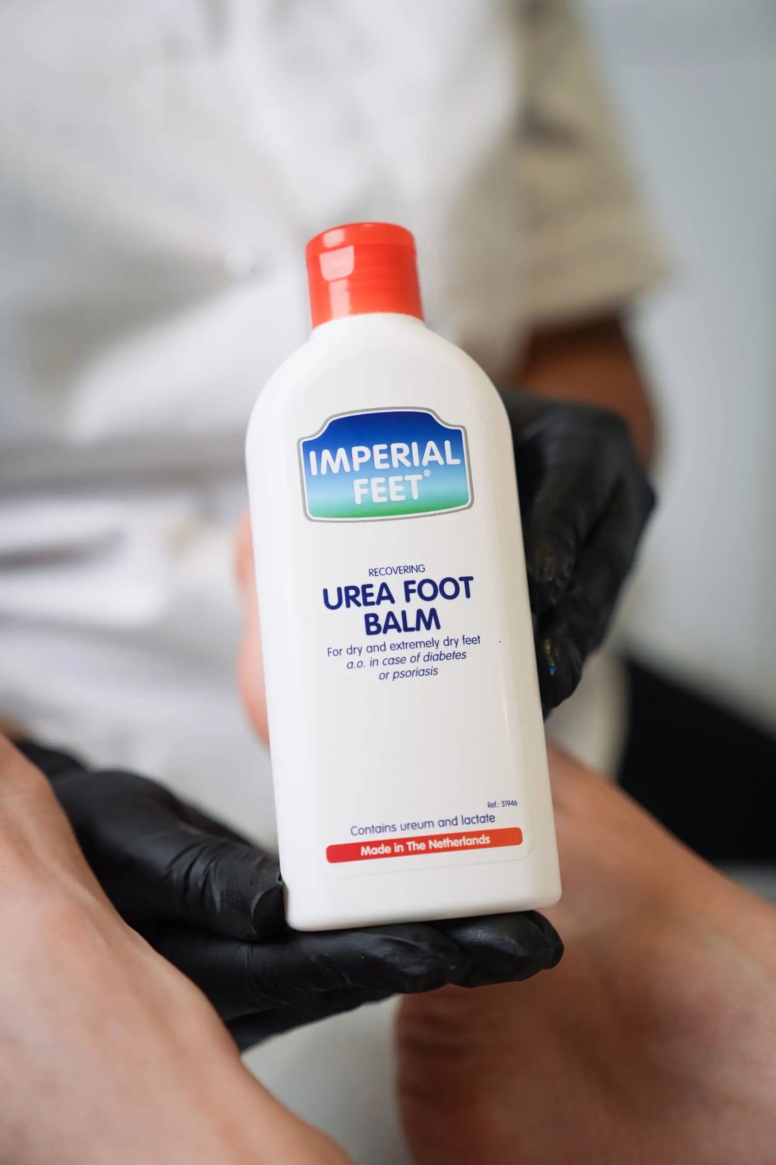 Een fles Urea foot balm wordt boven een voet vastgehouden.