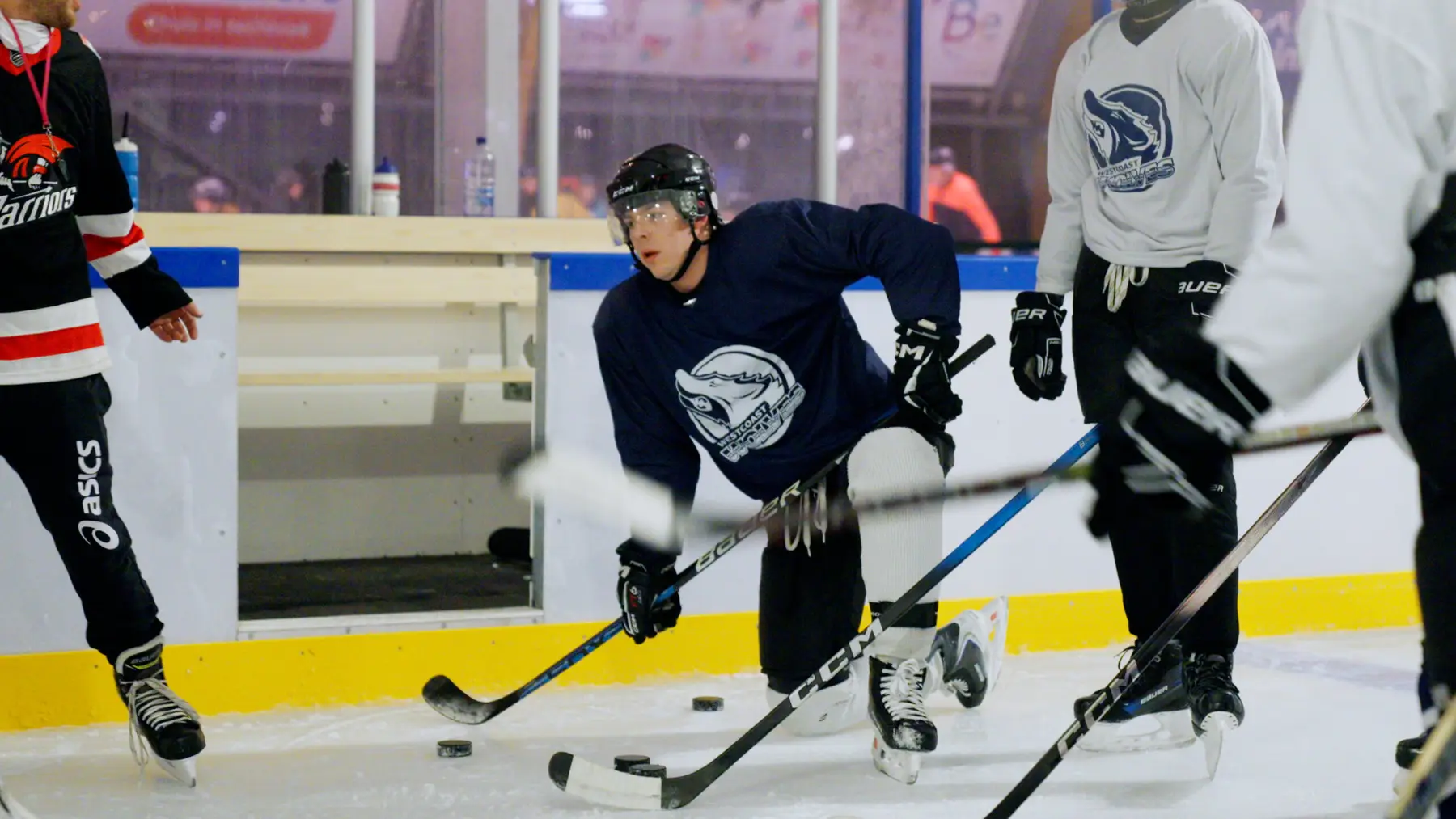 IJshockeyers strijden om de puck langs de boarding.
