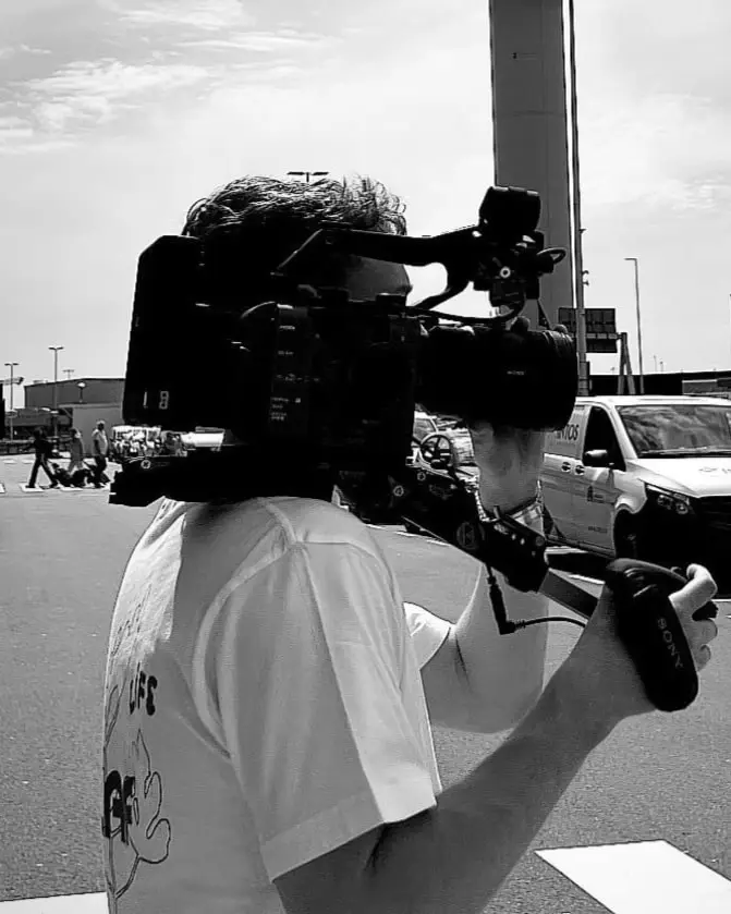 Zwart-witfoto van een cameraman met een schoudercamera op straat.