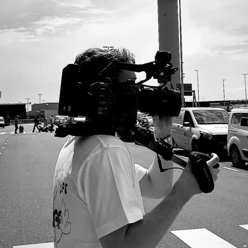 Zwart-witfoto van een cameraman met een schoudercamera op straat.