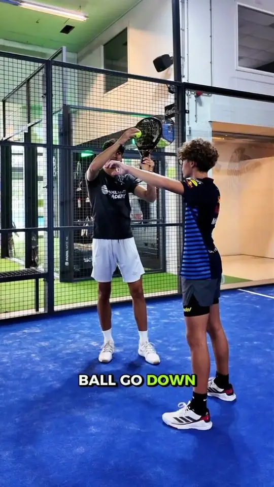 Reelcover van Padel Mate Academy: een coach geeft een speler uitleg, met de tekst Ball go down.
