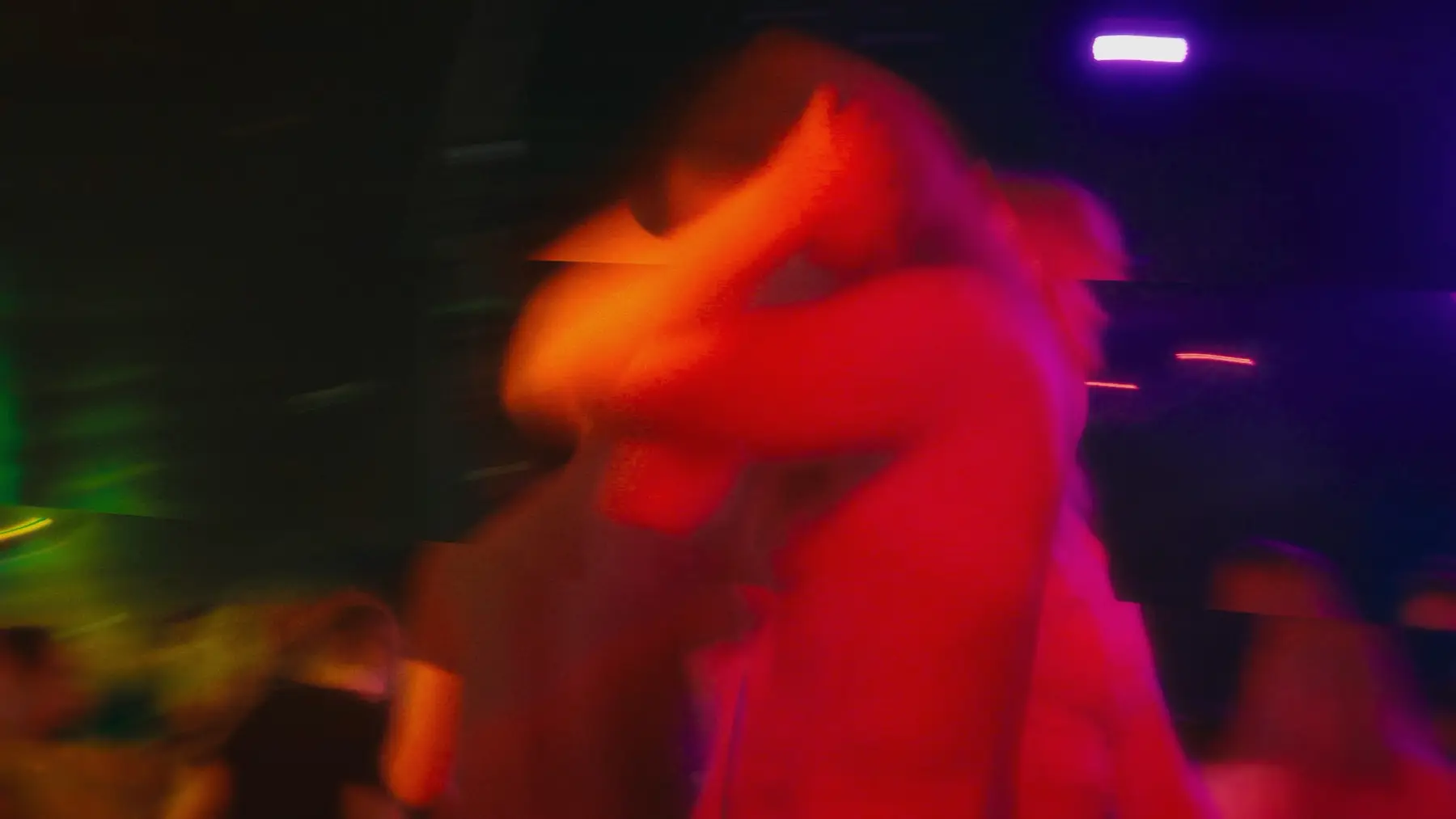Bewogen beeld van een dansend publiek in rood en oranje licht.