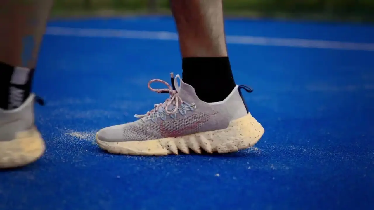 Close-up van een sneaker op een blauwe padelbaan.